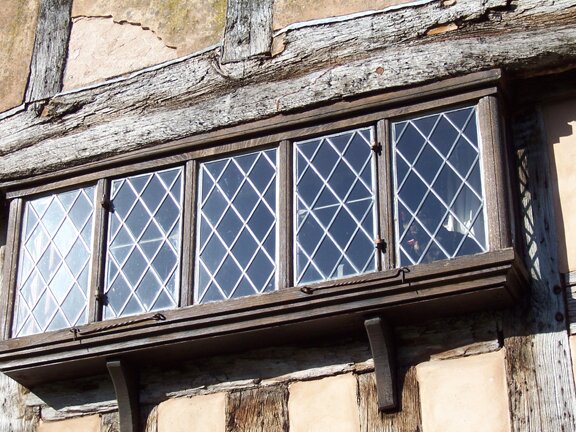 A cat sits quietly in the window of a timber frame house in Pembridge